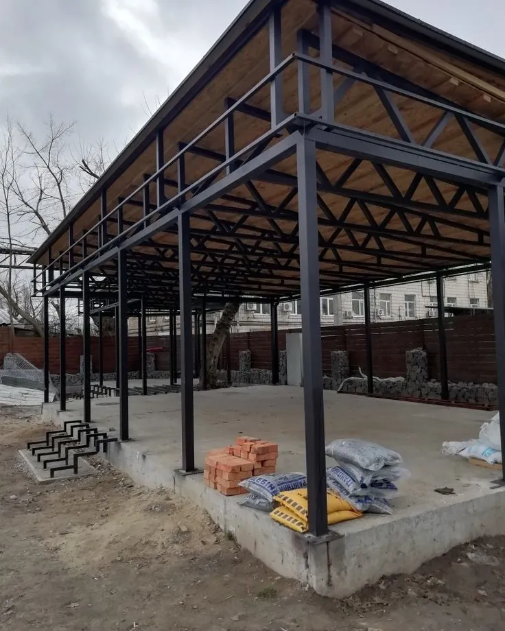 Estructura metálica terminada, con columnas y cabreadas de hierro y cubierta de madera, sobre platea de hormigón